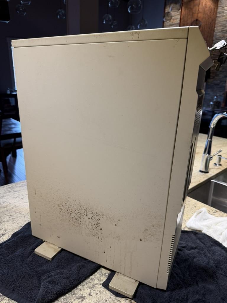 The side of an Amiga 3000T standing on the kitchen counter. The machine is off-white and about the size of the largest parts of Stonehenge. The lower third of the case is especially streaked with dark stains from decades of storage.
